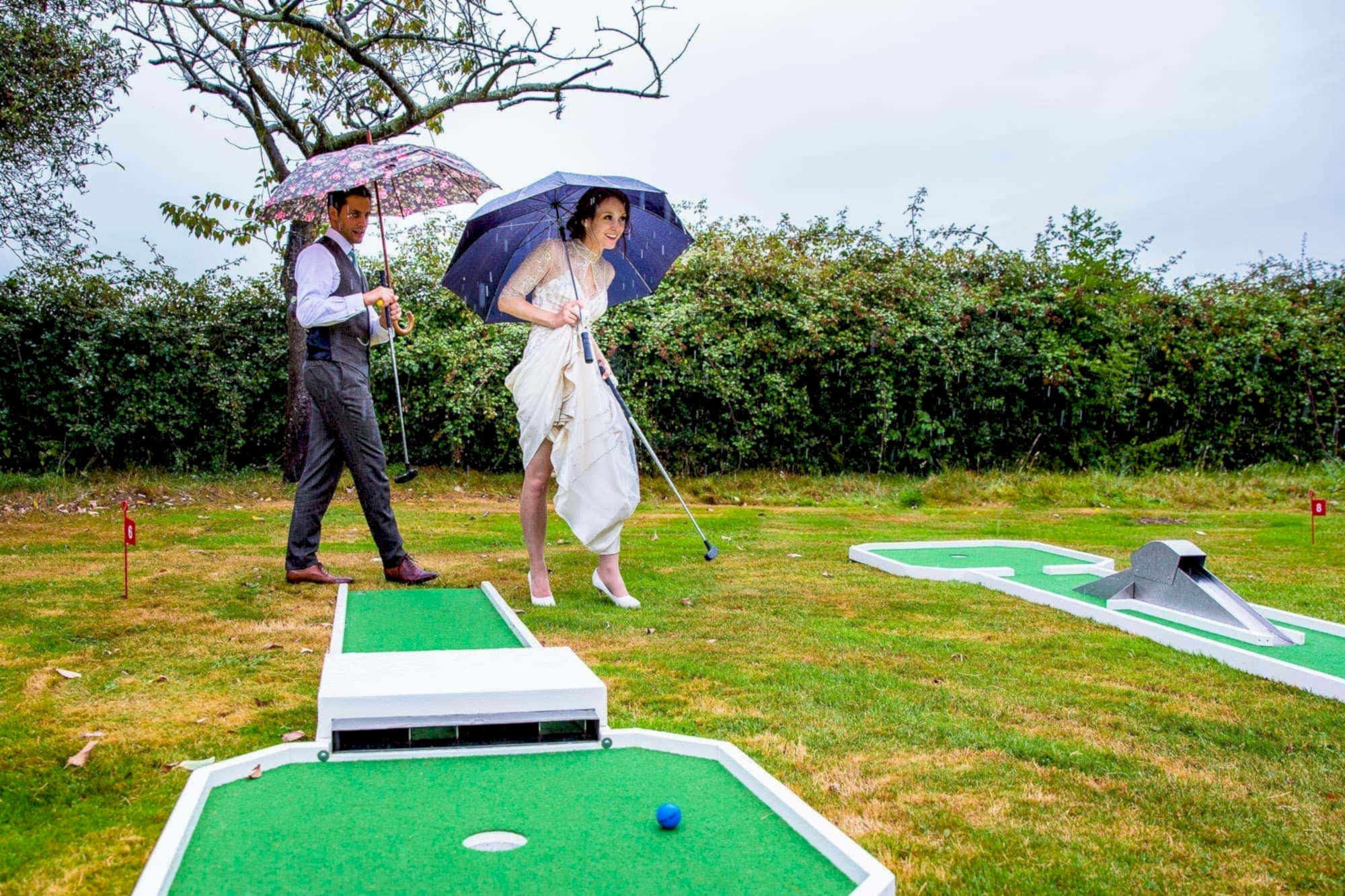 Bride and Groom playing crazy golf in the rain - Rotherwick Village Hall wedding
