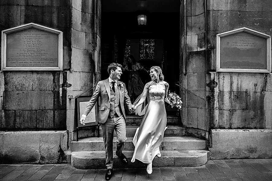 Couple exiting the church by London Wedding Photographers Carol & Paul Tansley. BW image.